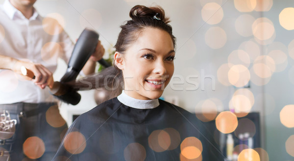 happy woman with stylist making hairdo at salon Stock photo © dolgachov