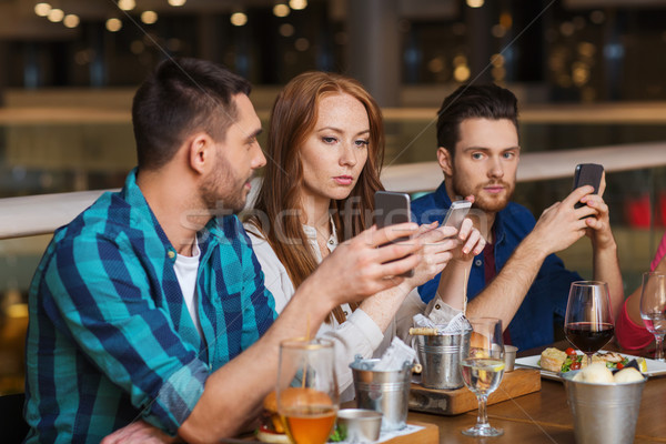 friends with smartphones dining at restaurant Stock photo © dolgachov