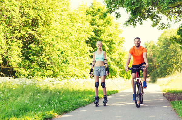 happy couple with rollerskates and bicycle riding Stock photo © dolgachov