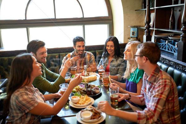 friends dining and drinking beer at restaurant Stock photo © dolgachov