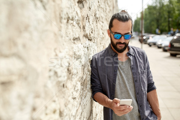 man texting message on smartphone at stone wall Stock photo © dolgachov