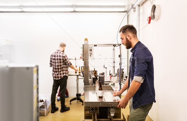 men with bottles on conveyor at craft beer brewery Stock photo © dolgachov