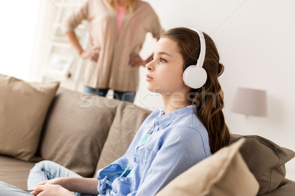 girl with earphones and angry mother at home Stock photo © dolgachov