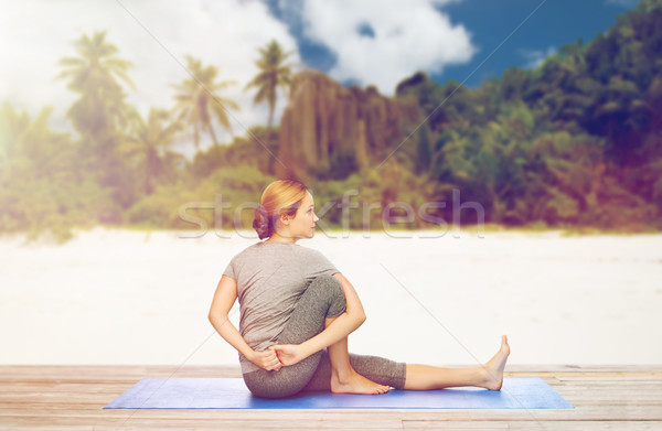 woman doing yoga in twist pose on beach Stock photo © dolgachov