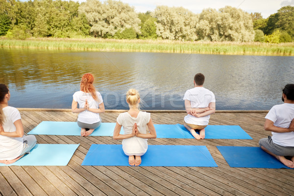 group of people making yoga exercises outdoors Stock photo © dolgachov