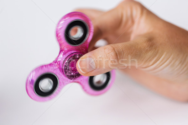 Stock photo: close up of hand playing with fidget spinner