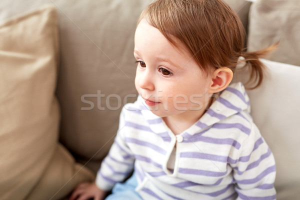close up of baby girl sitting on sofa at home Stock photo © dolgachov