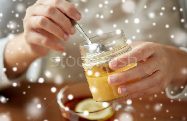 close up of woman adding honey to tea with lemon Stock photo © dolgachov