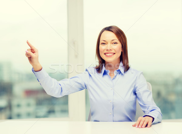 smiling woman pointing to something imaginary Stock photo © dolgachov