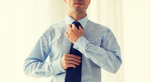 Stock photo: close up of man in shirt adjusting tie on neck