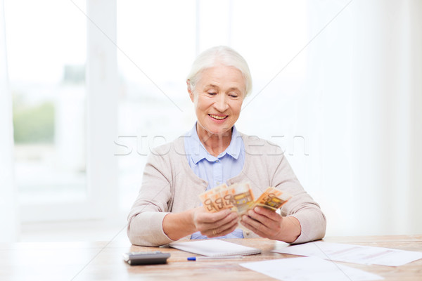 Stock photo: senior woman with money and papers at home