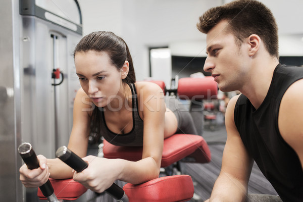 young woman with trainer exercising on gym machine Stock photo © dolgachov