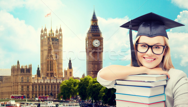 student in trencher cap with books over london Stock photo © dolgachov