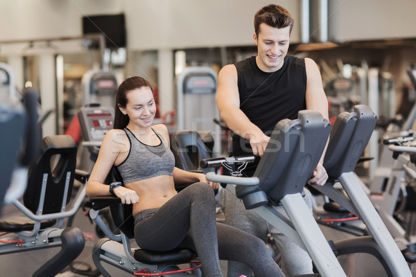 happy woman with trainer on exercise bike in gym Stock photo © dolgachov