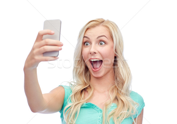 Stock photo: smiling young woman taking selfie with smartphone