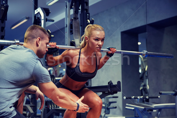 man and woman with bar flexing muscles in gym Stock photo © dolgachov