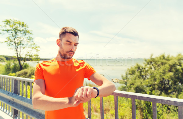 young man with smart wristwatch at seaside Stock photo © dolgachov