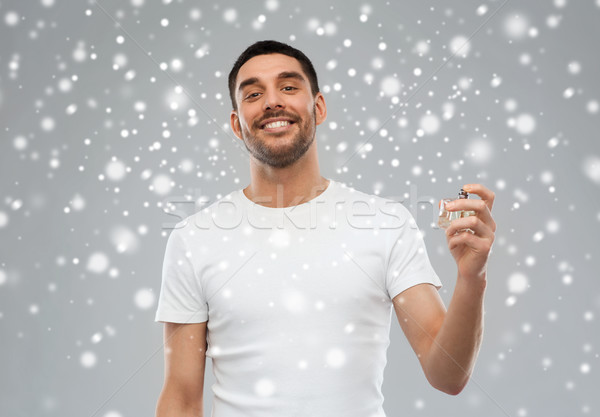 smiling man with male perfume over snow background Stock photo © dolgachov