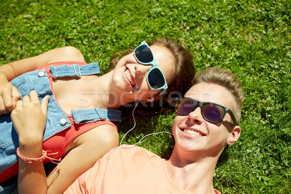 happy teenage couple with earphones lying on grass Stock photo © dolgachov
