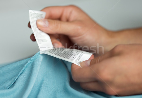 hands holding label with users manual of clothing Stock photo © dolgachov