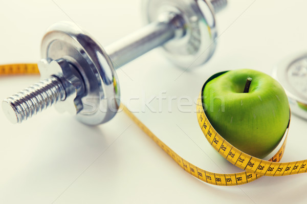 close up of dumbbell and apple with measuring tape Stock photo © dolgachov