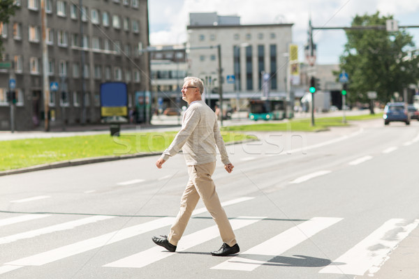 senior man walking along city crosswalk Stock photo © dolgachov