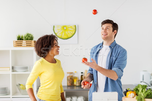 couple cooking food and juggling tomatoes at home Stock photo © dolgachov