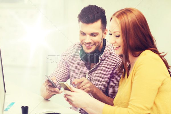 smiling creative team with smartphones at office Stock photo © dolgachov