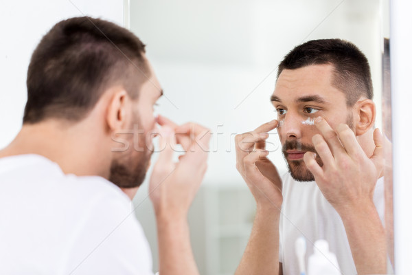 young man applying cream to face at bathroom Stock photo © dolgachov