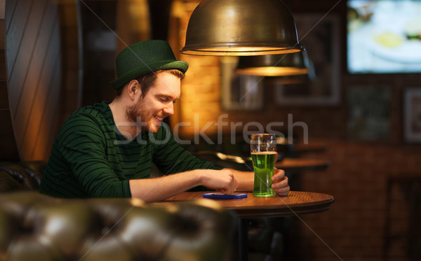 man with smartphone and green beer at bar or pub Stock photo © dolgachov