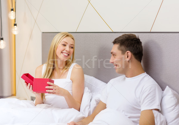 smiling couple in bed with red gift box Stock photo © dolgachov
