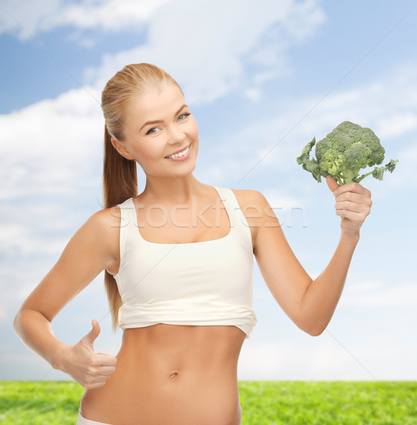 Stock photo: woman pointing at her abs and holding broccoli