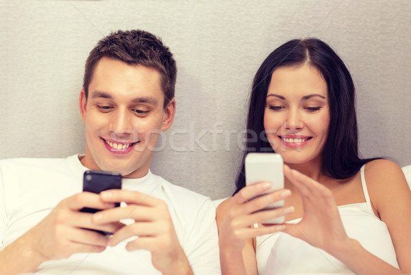 smiling couple in bed with smartphones Stock photo © dolgachov