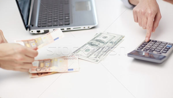 Stock photo: close up of hands counting money with calculator