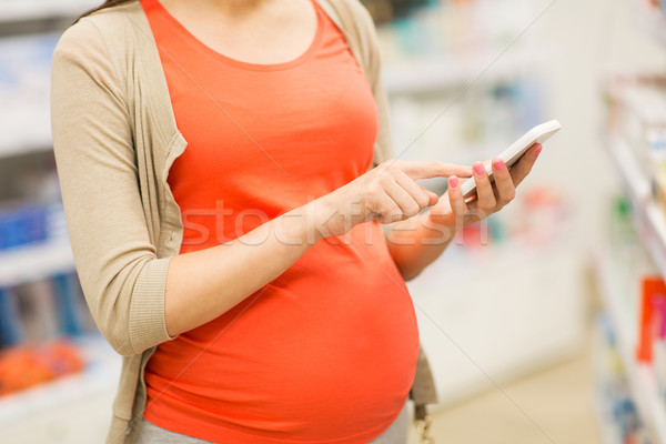 pregnant woman with smartphone at pharmacy Stock photo © dolgachov
