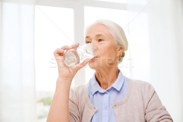 Stock photo: happy senior woman with glass of water at home