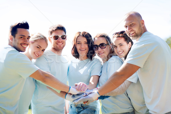 group of volunteers putting hands on top in park Stock photo © dolgachov