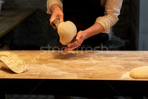 baker portioning dough with bench cutter at bakery Stock photo © dolgachov