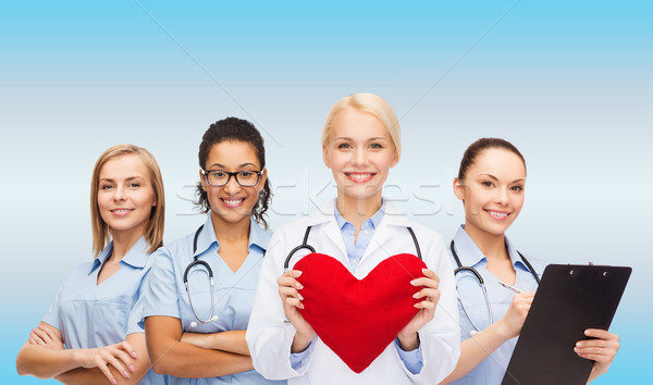 smiling female doctor and nurses with red heart Stock photo © dolgachov