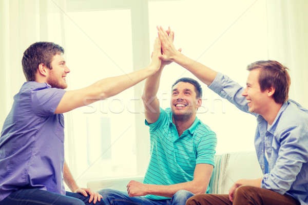 улыбаясь мужчины друзей high five домой команде Сток-фото © dolgachov