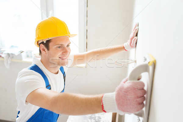 Stock photo: smiling builder with grinding tool indoors
