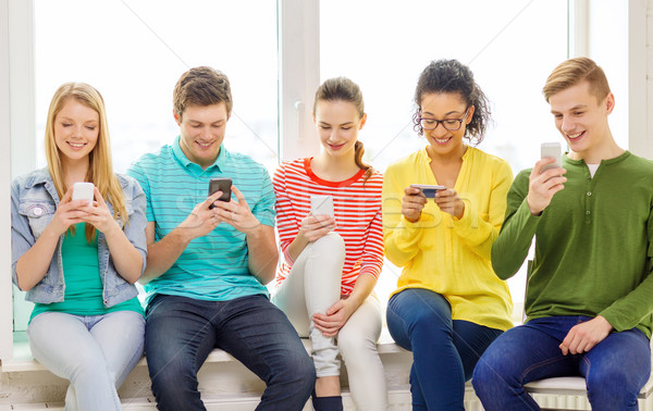 smiling students with smartphone texting at school Stock photo © dolgachov