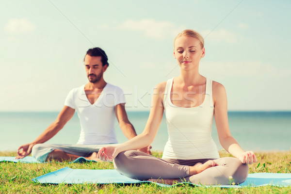 smiling couple making yoga exercises outdoors Stock photo © dolgachov