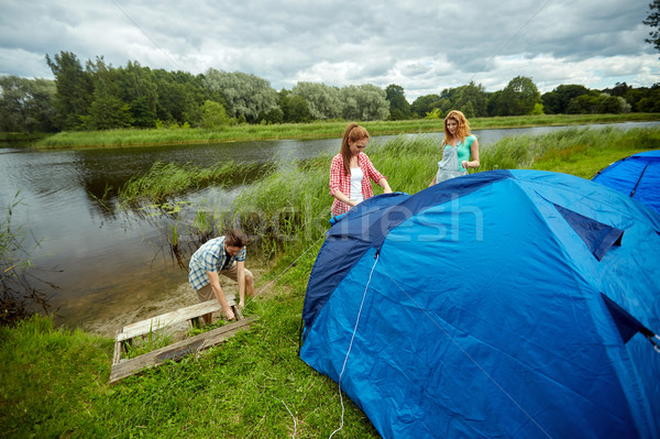 group of smiling friends setting up tent outdoors Stock photo © dolgachov