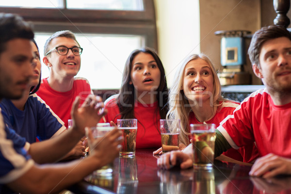 Stock photo: fans or friends watching football at sport bar