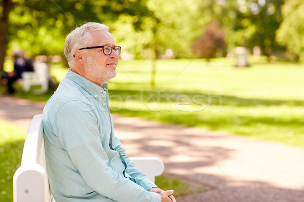 happy senior man in glasses sitting at summer park Stock photo © dolgachov