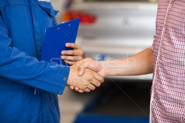 Stock photo: auto mechanic and man shaking hands at car shop