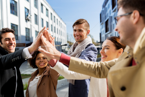 group of happy people making high five in city Stock photo © dolgachov