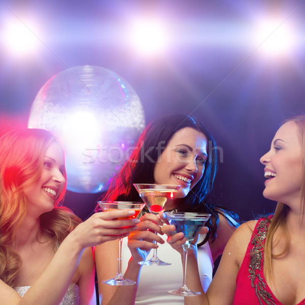 three smiling women with cocktails and disco ball Stock photo © dolgachov