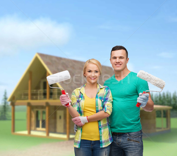 smiling couple in gloves with paint rollers Stock photo © dolgachov